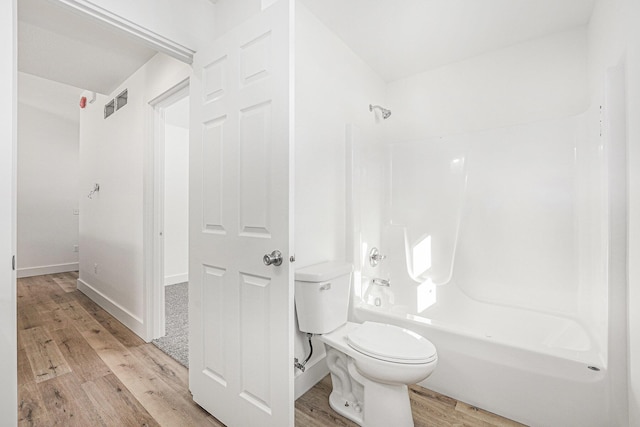 bathroom with shower / bath combination, hardwood / wood-style floors, and toilet