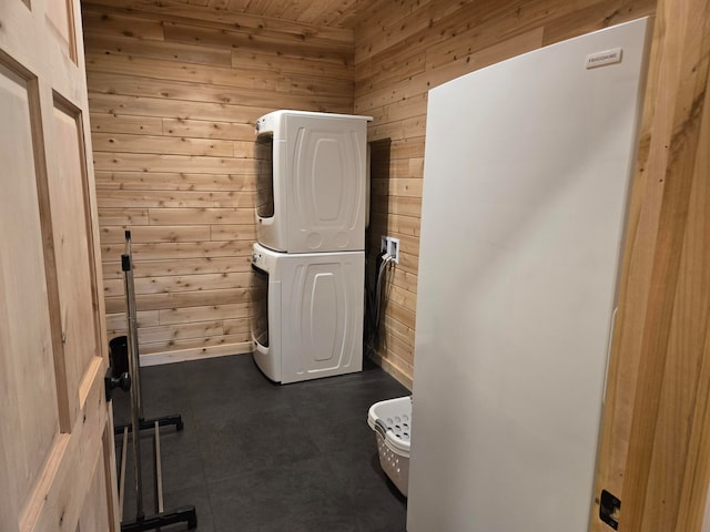 clothes washing area featuring wooden walls, stacked washer and dryer, and wooden ceiling