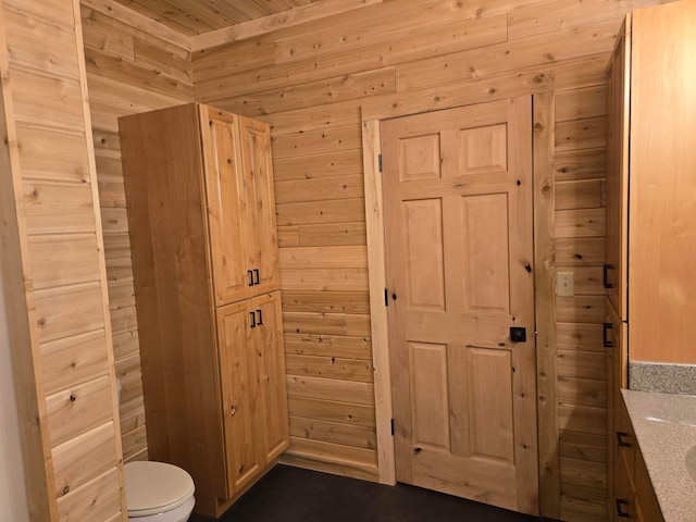 bathroom featuring wooden ceiling, vanity, wooden walls, and toilet