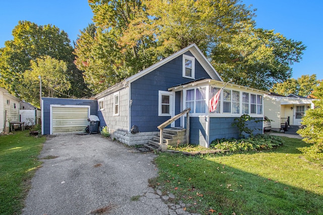 bungalow-style home with a front lawn, an outbuilding, and a garage