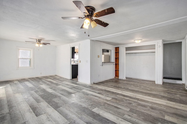 unfurnished living room featuring a textured ceiling, wood-type flooring, and ceiling fan