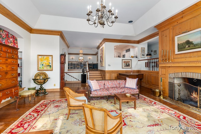 living room with dark hardwood / wood-style flooring, a chandelier, a tray ceiling, a fireplace, and crown molding