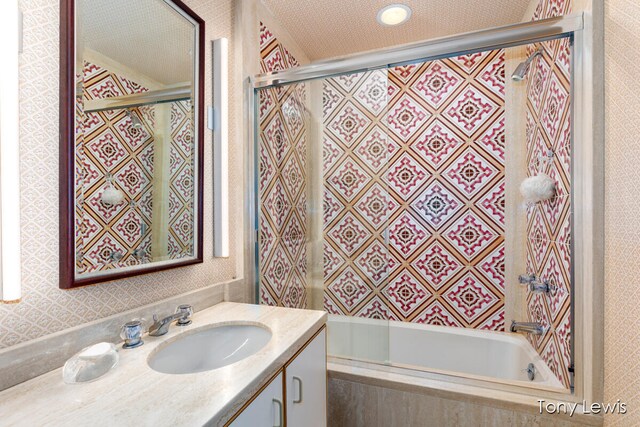 bathroom with vanity, enclosed tub / shower combo, and a textured ceiling