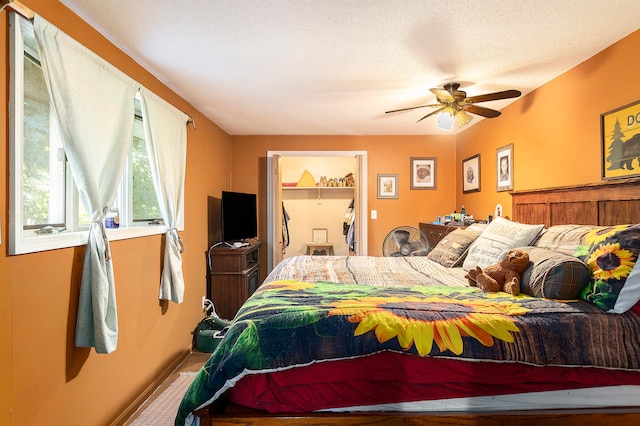 carpeted bedroom featuring a spacious closet, a closet, a textured ceiling, and ceiling fan