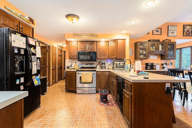 kitchen featuring sink, a textured ceiling, black appliances, a center island, and a kitchen bar