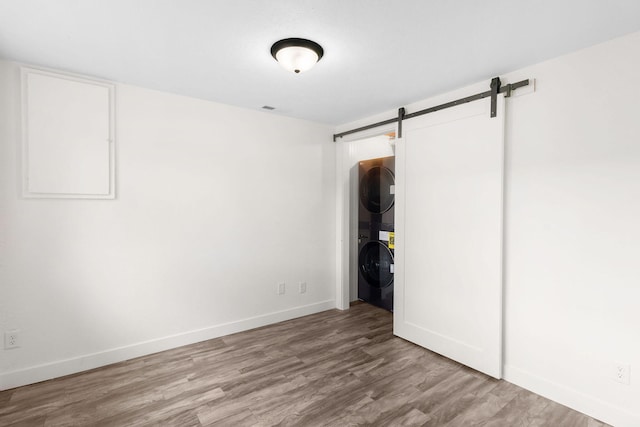 interior space with a barn door, light hardwood / wood-style flooring, and stacked washer / drying machine