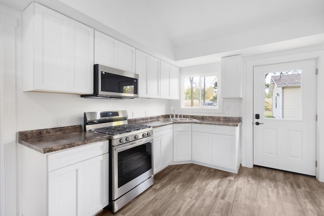 kitchen featuring white cabinets, lofted ceiling, sink, stainless steel appliances, and light hardwood / wood-style floors