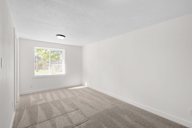 carpeted empty room featuring a textured ceiling