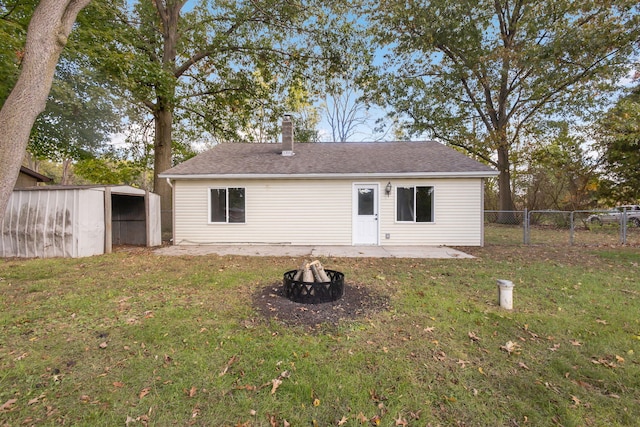 rear view of property featuring an outdoor fire pit, a yard, and a patio area