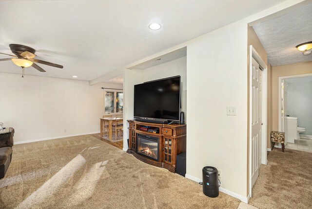 living room featuring carpet, a textured ceiling, and ceiling fan