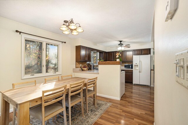 dining space with dark wood-type flooring, a textured ceiling, and ceiling fan with notable chandelier