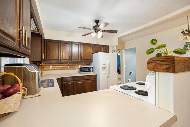 kitchen with white appliances, tasteful backsplash, dark brown cabinets, kitchen peninsula, and ceiling fan