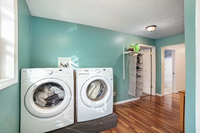 washroom featuring dark wood-type flooring, washing machine and dryer, and a textured ceiling