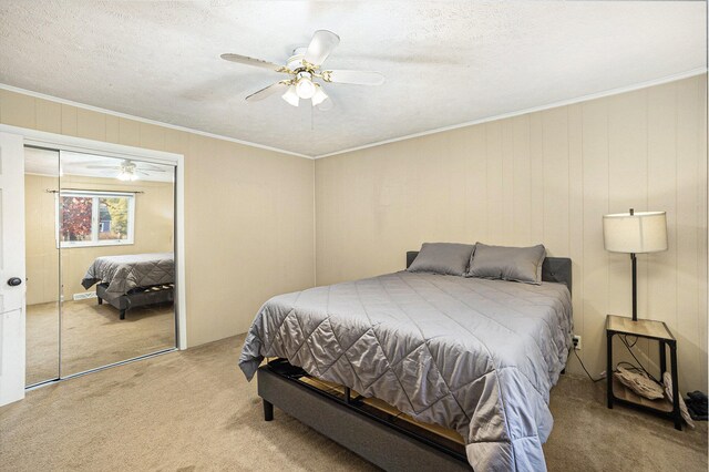 carpeted bedroom featuring a closet, ceiling fan, crown molding, and a textured ceiling