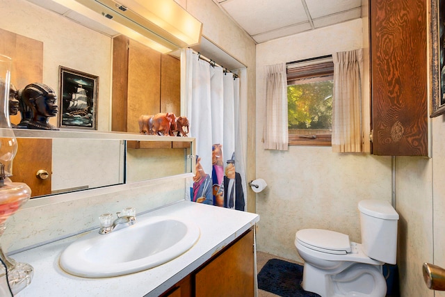 bathroom with toilet, a drop ceiling, and vanity