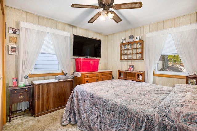 bedroom featuring light carpet, wooden walls, and ceiling fan