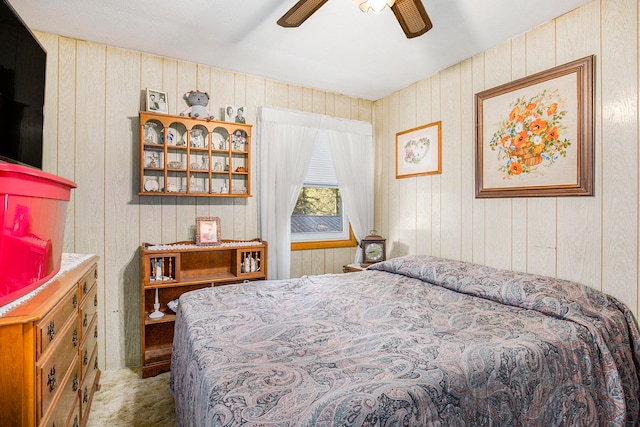 bedroom featuring ceiling fan, carpet, and wooden walls