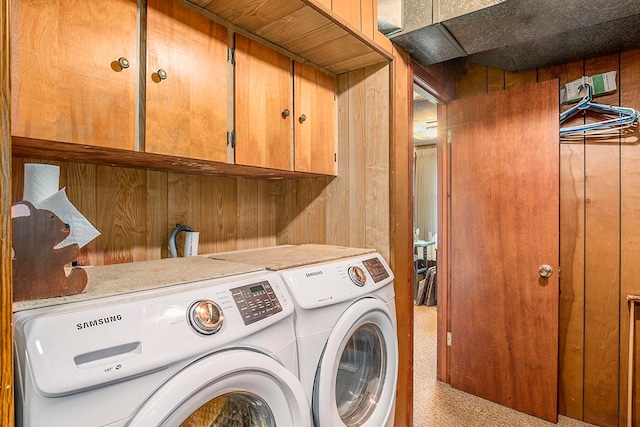 laundry room with wood walls, independent washer and dryer, and cabinets