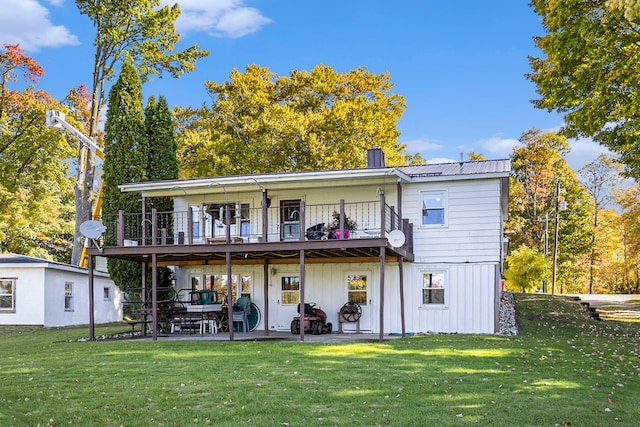 rear view of house with a balcony, a yard, and a patio