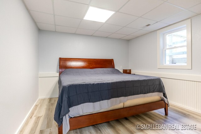 bedroom featuring light hardwood / wood-style floors and a paneled ceiling