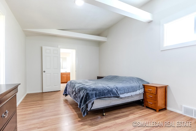 bedroom featuring connected bathroom, vaulted ceiling, and light wood-type flooring