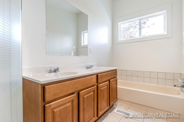 bathroom with a wealth of natural light, vanity, a bath, and tile patterned floors