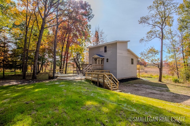 rear view of house featuring a wooden deck and a yard