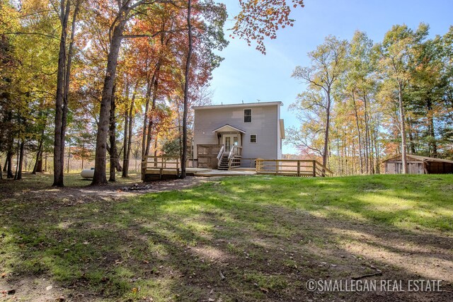 rear view of house with a storage shed, a wooden deck, and a lawn