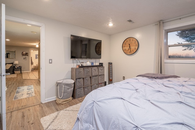 bedroom with light hardwood / wood-style flooring and a textured ceiling