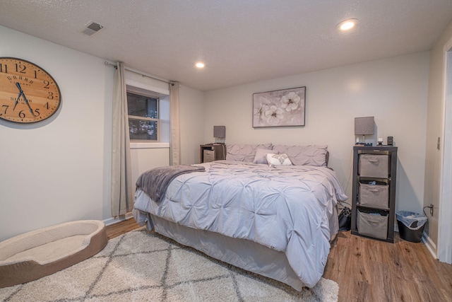 bedroom featuring light hardwood / wood-style floors and a textured ceiling