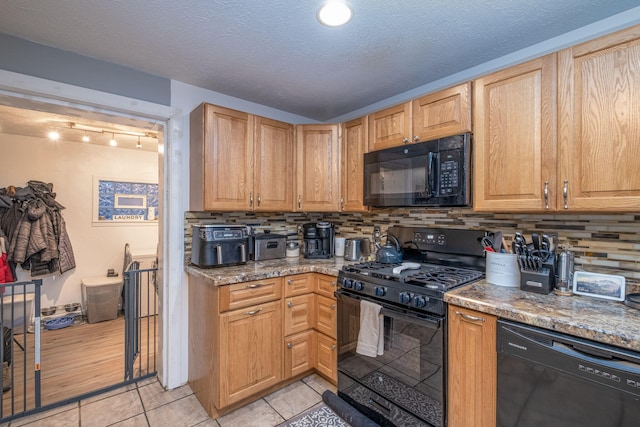 kitchen featuring tasteful backsplash, black appliances, stone counters, and light tile patterned floors