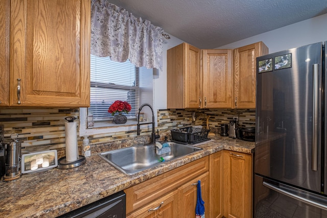 kitchen with appliances with stainless steel finishes, sink, backsplash, a textured ceiling, and dark stone countertops