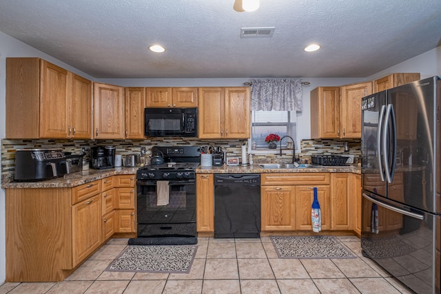 kitchen featuring backsplash, black appliances, sink, and light tile patterned floors