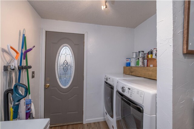 washroom featuring a textured ceiling, washing machine and dryer, and light hardwood / wood-style floors