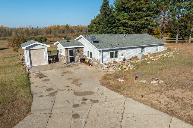 single story home featuring an outbuilding, a garage, and central AC unit