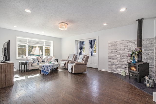 living room featuring a textured ceiling, dark hardwood / wood-style flooring, a wealth of natural light, and a wood stove