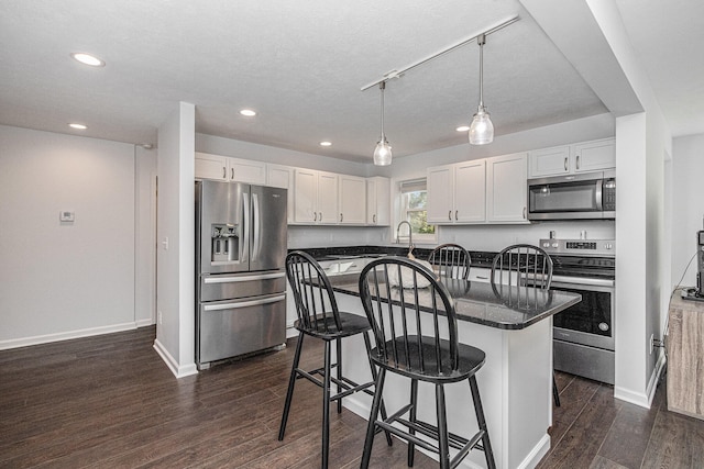 kitchen with a kitchen island, a breakfast bar area, dark wood-type flooring, stainless steel appliances, and white cabinets