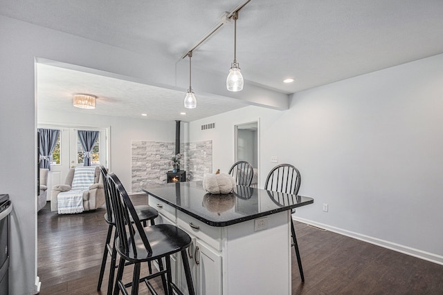 kitchen featuring pendant lighting, a kitchen island, dark hardwood / wood-style flooring, white cabinets, and a kitchen bar