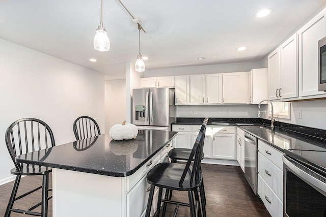 kitchen with appliances with stainless steel finishes, dark wood-type flooring, white cabinetry, and a center island