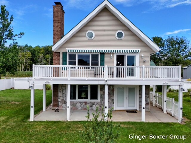 back of property featuring a deck, a lawn, and a patio area