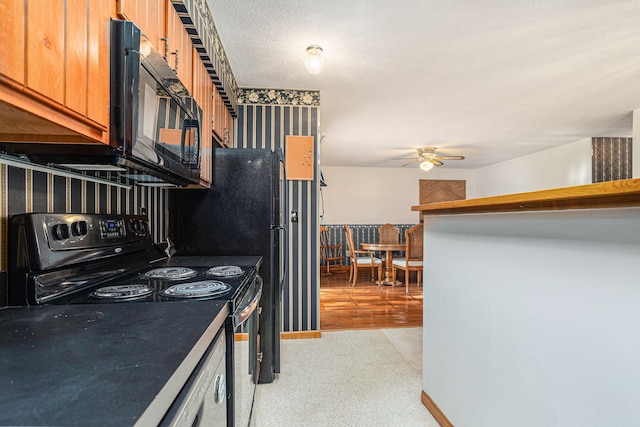 kitchen featuring light hardwood / wood-style floors, a textured ceiling, black appliances, and ceiling fan