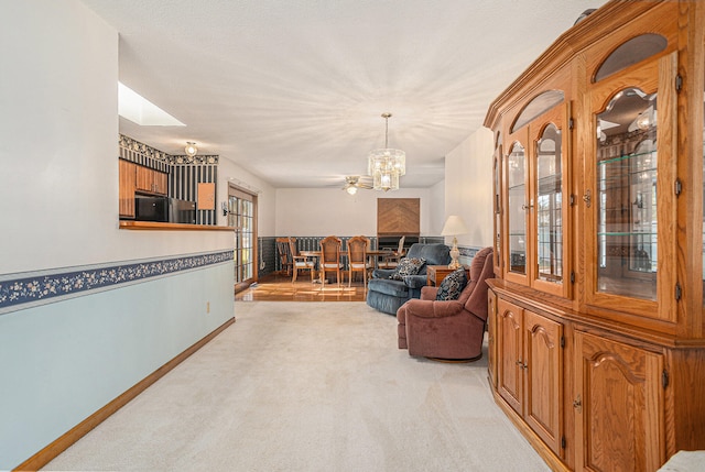 sitting room featuring a skylight, light carpet, a textured ceiling, and ceiling fan