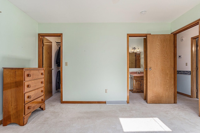 carpeted bedroom with a spacious closet, connected bathroom, a closet, and sink