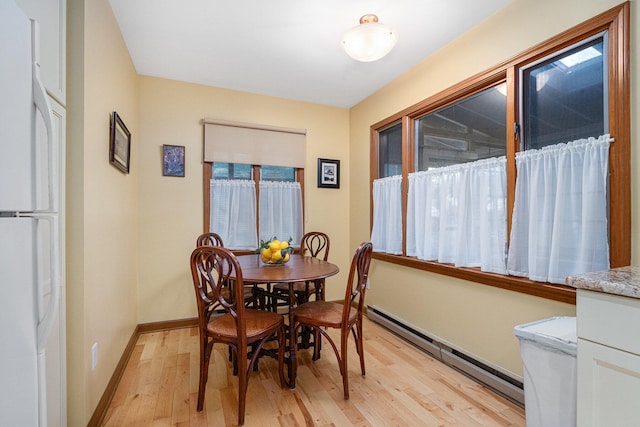 dining room with light wood-type flooring, plenty of natural light, and baseboard heating