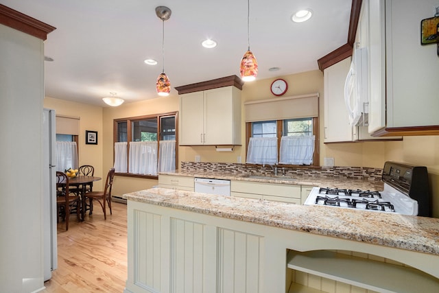 kitchen featuring light stone counters, a wealth of natural light, white appliances, hanging light fixtures, and white cabinetry