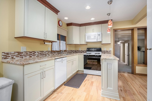 kitchen with light stone counters, white appliances, decorative light fixtures, white cabinetry, and light hardwood / wood-style floors