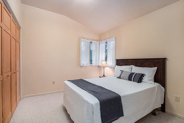 bedroom with lofted ceiling, a closet, and light carpet