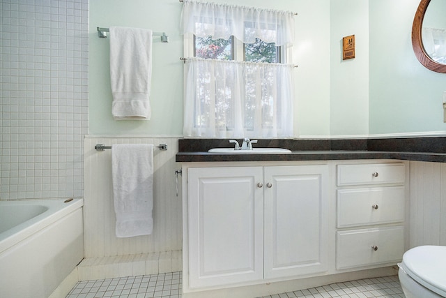 bathroom featuring toilet, a tub to relax in, tile patterned floors, tile walls, and vanity