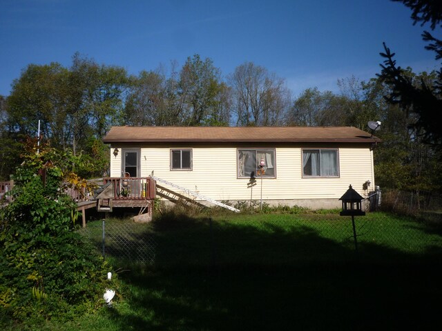 rear view of property featuring a deck and a lawn