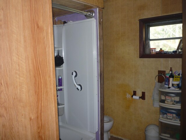 bathroom featuring walk in shower, tile walls, and toilet